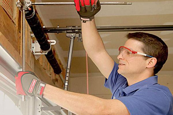 man adjusting garage door cables inside a garage